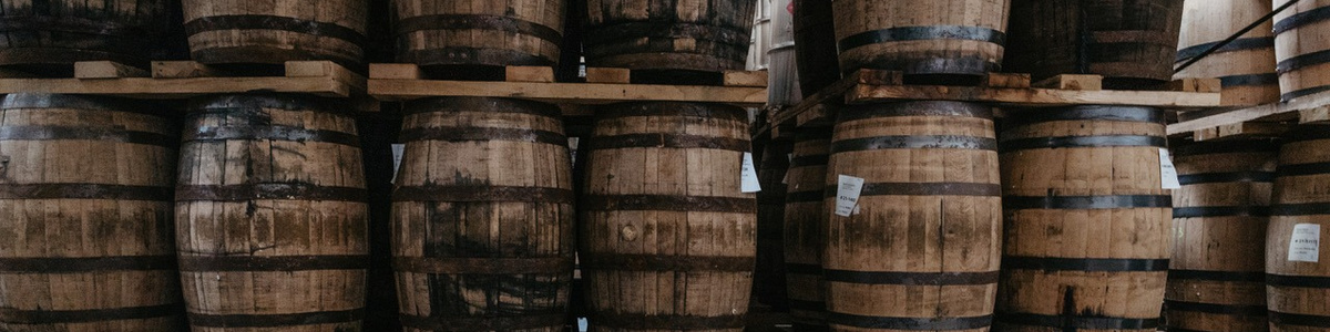 Wooden whiskey barrels stacked in the Barrell Craft Spirits warehouse.